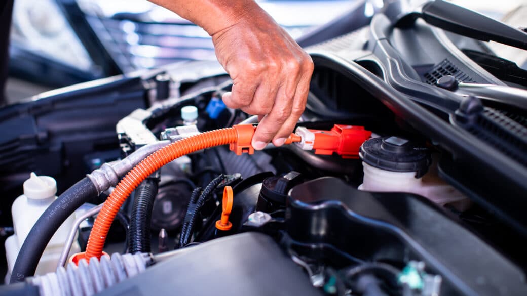 Mechanic holding car battery cable in engine bay
