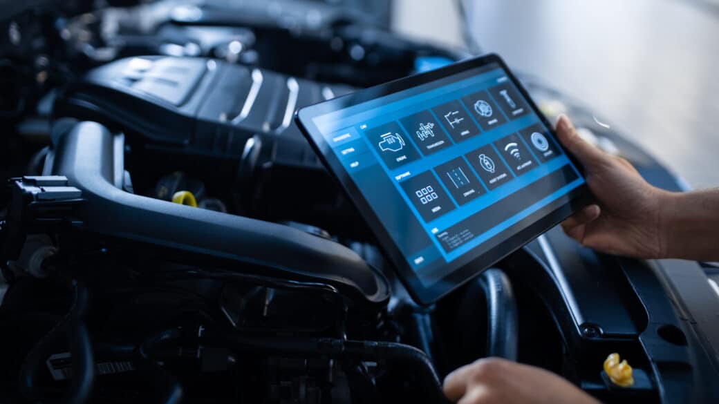 Mechanic running car diagnostics using tablet in engine bay